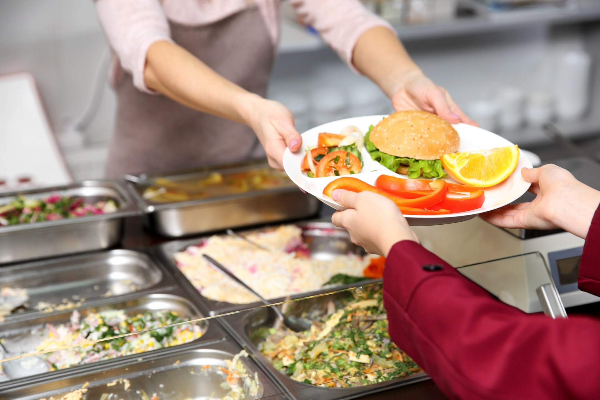 a person handing a plate of food to another person